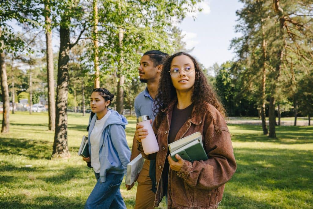 Trois jeunes gens avec cartables en mains semblent en route pour l'école