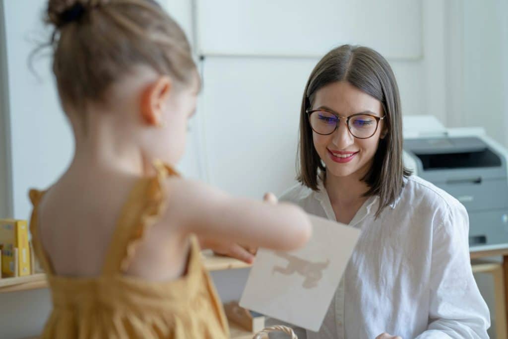 Une femme sourit en regardantune feuille de papier sur laquelle figure un dessin réalisé par un enfant, qui est au premier-plan.