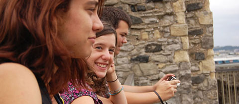 Trois jeunes de profil don t l'une des personnes regardent et sourient à la caméra