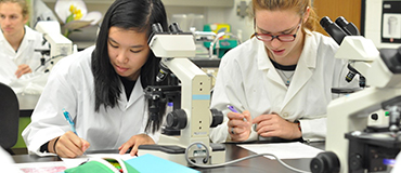 2 filles en sarrau avec microscope